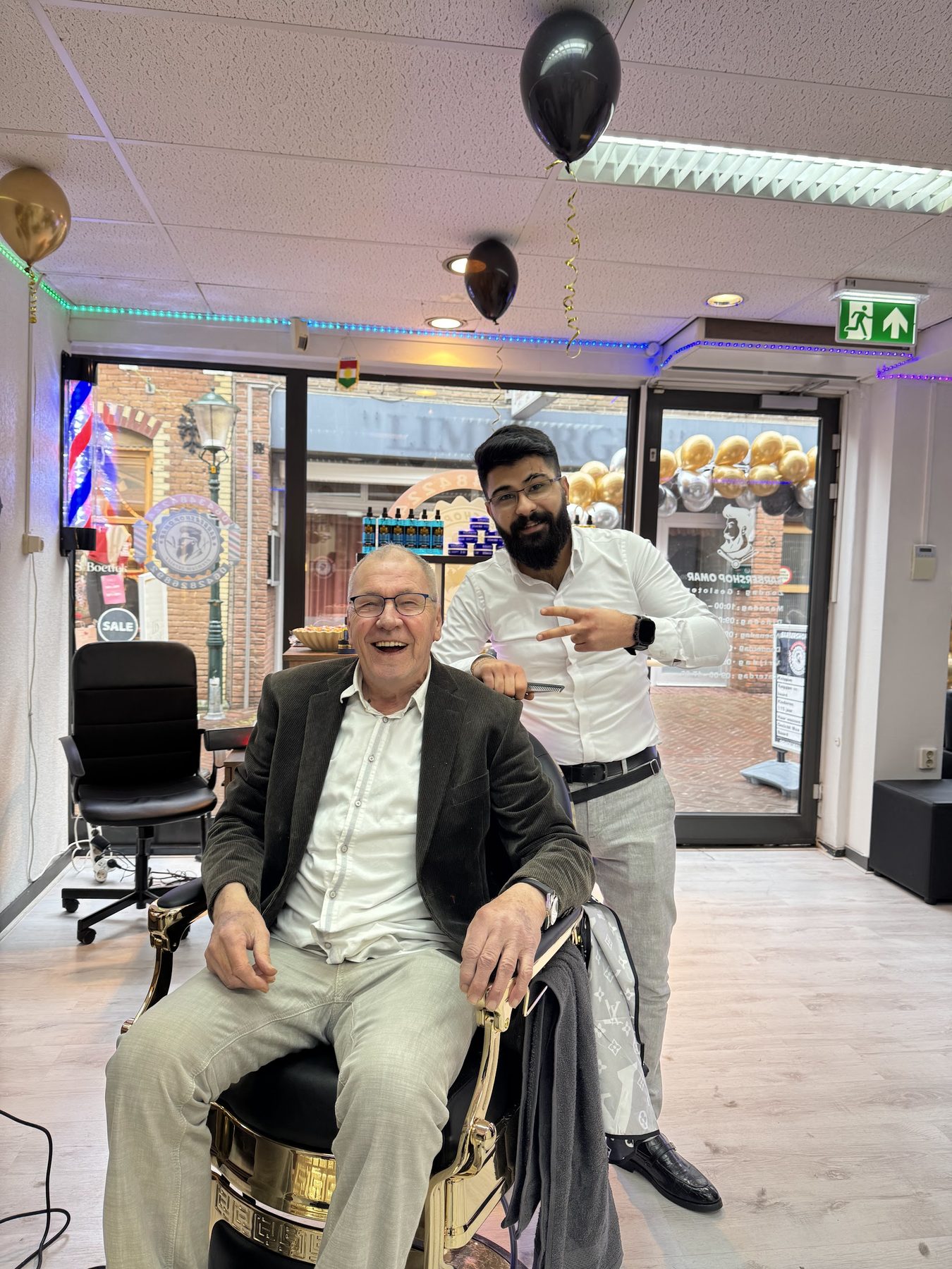 Een lachende klant in de stoel met de barbier naast hem